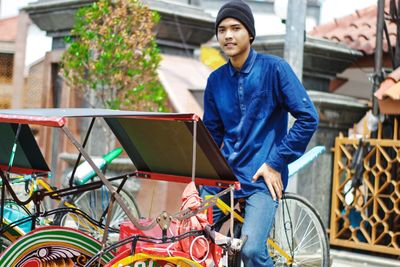 Portrait of young man standing against bus