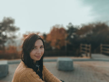 Portrait of smiling woman standing against sky