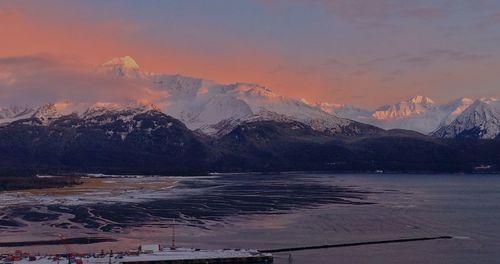 Scenic view of lake by mountains against sky during sunset