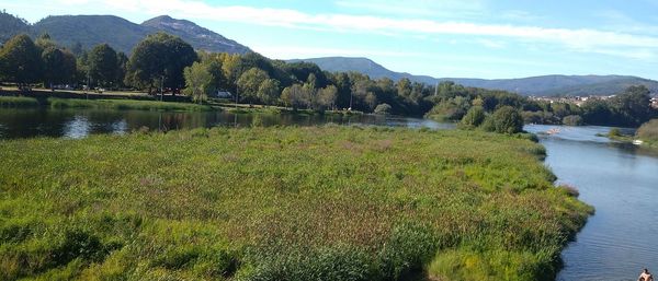 Scenic view of river by mountains against sky