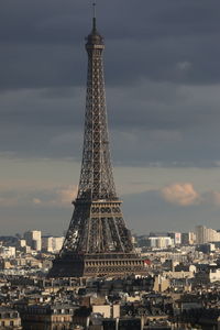 Communications tower in city against sky