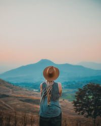 Rear view of woman standing on field against sky