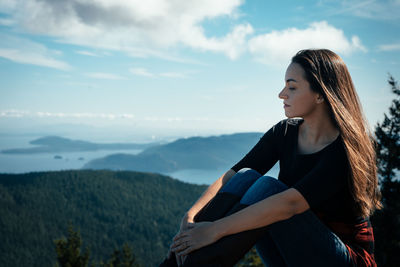 Woman sitting against blue sky