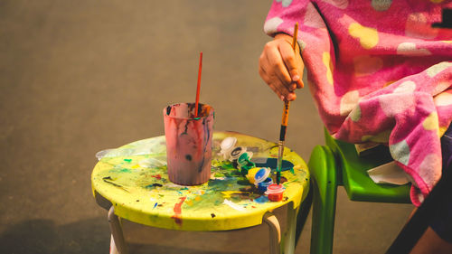 Little artist is dipping a paint brush into a watercolor palette. a kid with palette and brushes. 