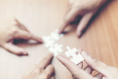 Close-up of hands playing jigsaw puzzle on table