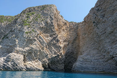 Rock formations by sea against sky