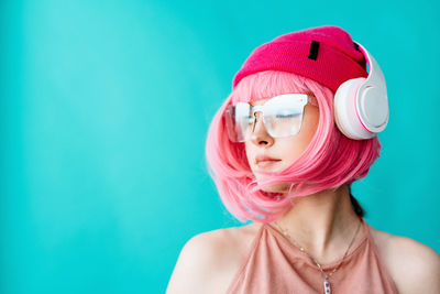 Modern youth culture. portrait of a girl with a short pink haircut on a blue background.