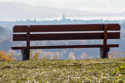 Empty bench on field against sky