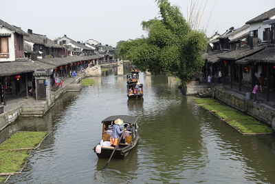 People on boat in river against clear sky