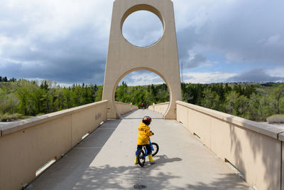 Young boy riding his bike on a bridge