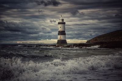 Lighthouse amidst sea and buildings against sky