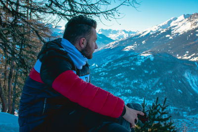 Side view of young man against snowcapped mountain