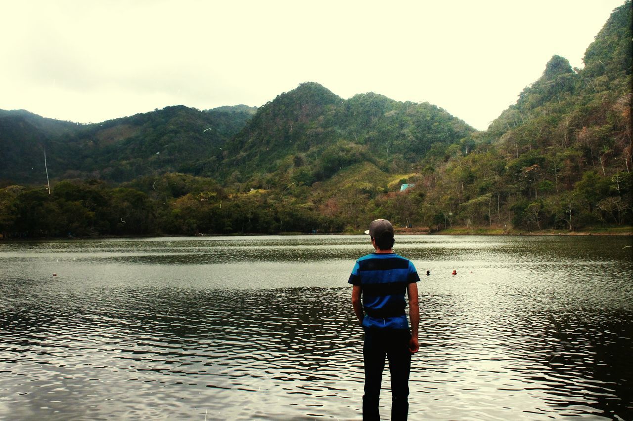 water, mountain, lake, rear view, leisure activity, lifestyles, tranquil scene, tranquility, standing, scenics, beauty in nature, nature, casual clothing, tree, men, river, three quarter length, full length