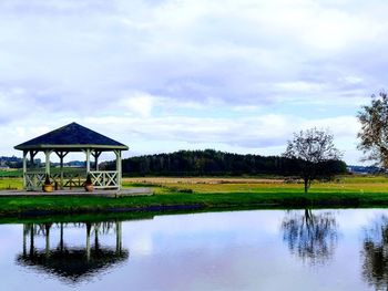 Gazebo by lake against sky