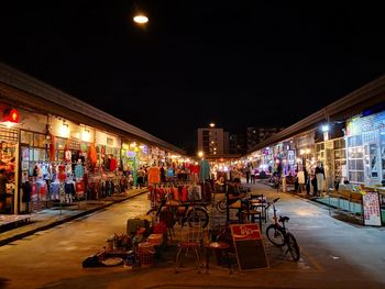 People at illuminated market in city at night