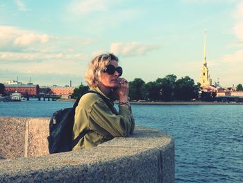 Woman sitting by sunglasses against sky