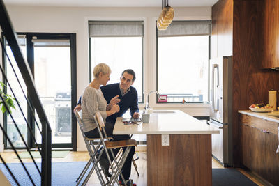 Senior couple discussing while sitting by laptop computer at home