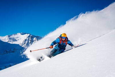 Man skiing on snowcapped mountain against sky