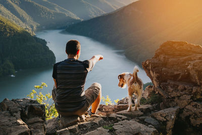 Rear view of woman with dog on rock