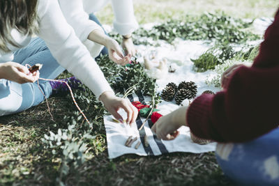 Midsection of people making wreath