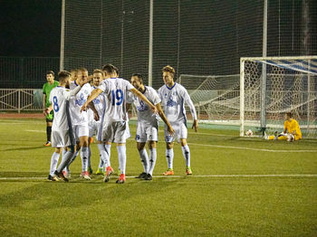 Rear view of people walking on soccer field