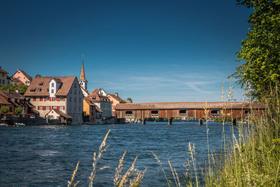 Houses by buildings against clear blue sky