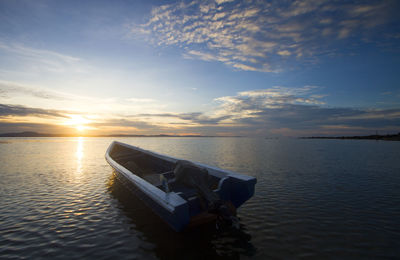 Boat moored on sea against sky during sunset