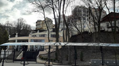 Bare trees in park against buildings in city