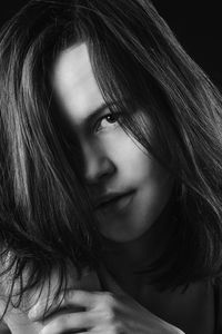 Close-up portrait of young woman against black background