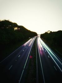 Light trails on road against clear sky