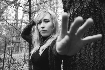 Portrait of young woman against tree trunk