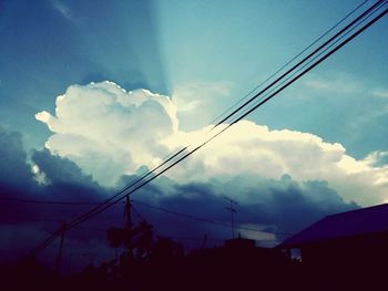 Low angle view of power lines against cloudy sky