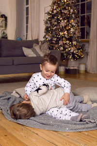 Two brothers in pajamas having fun on new year's eve next to the tree