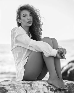 Portrait of beautiful woman sitting against sea against sky