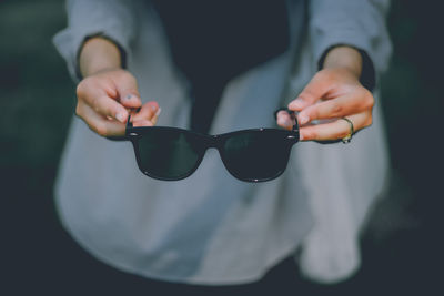 Close-up of hand holding sunglasses against blurred background