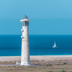 Lighthouse by sea against sky