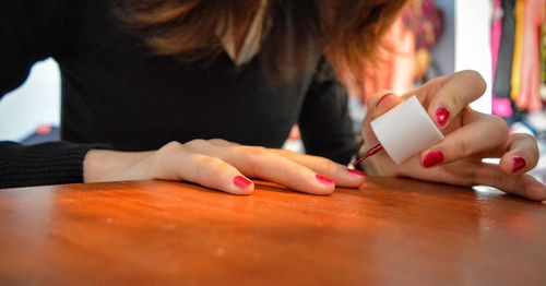 Midsection of woman applying nail polish