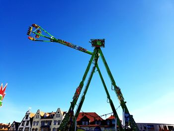 Low angle view of carousel by building against clear blue sky