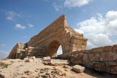 Low angle view of ancient roman aqueduct at caesarea beach against sky