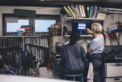 Female mechanics discussing over computer monitor at auto repair shop