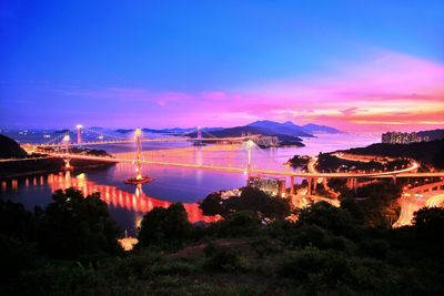 Illuminated bridge over river at night