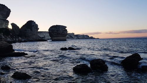 Rocks on sea against sky during sunset