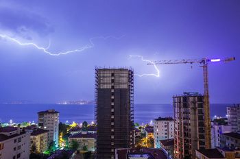 Lightning above sea and buildings in city