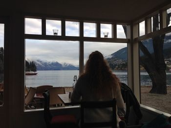 Rear view of woman looking through window