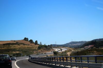 Road by mountain against clear blue sky
