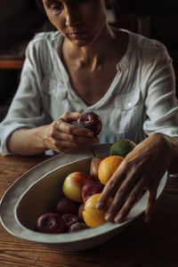 Middle aged sad woman with a bowl of fruits sitting at the table