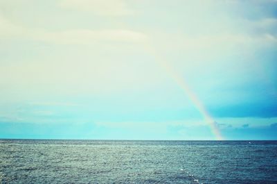 Scenic view of rainbow over sea against sky