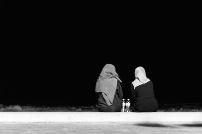 Rear view of female friends on beach against clear sky at night