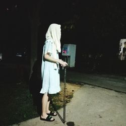 Woman standing with umbrella at night