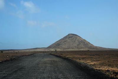 Road amidst desert against clear blue sky